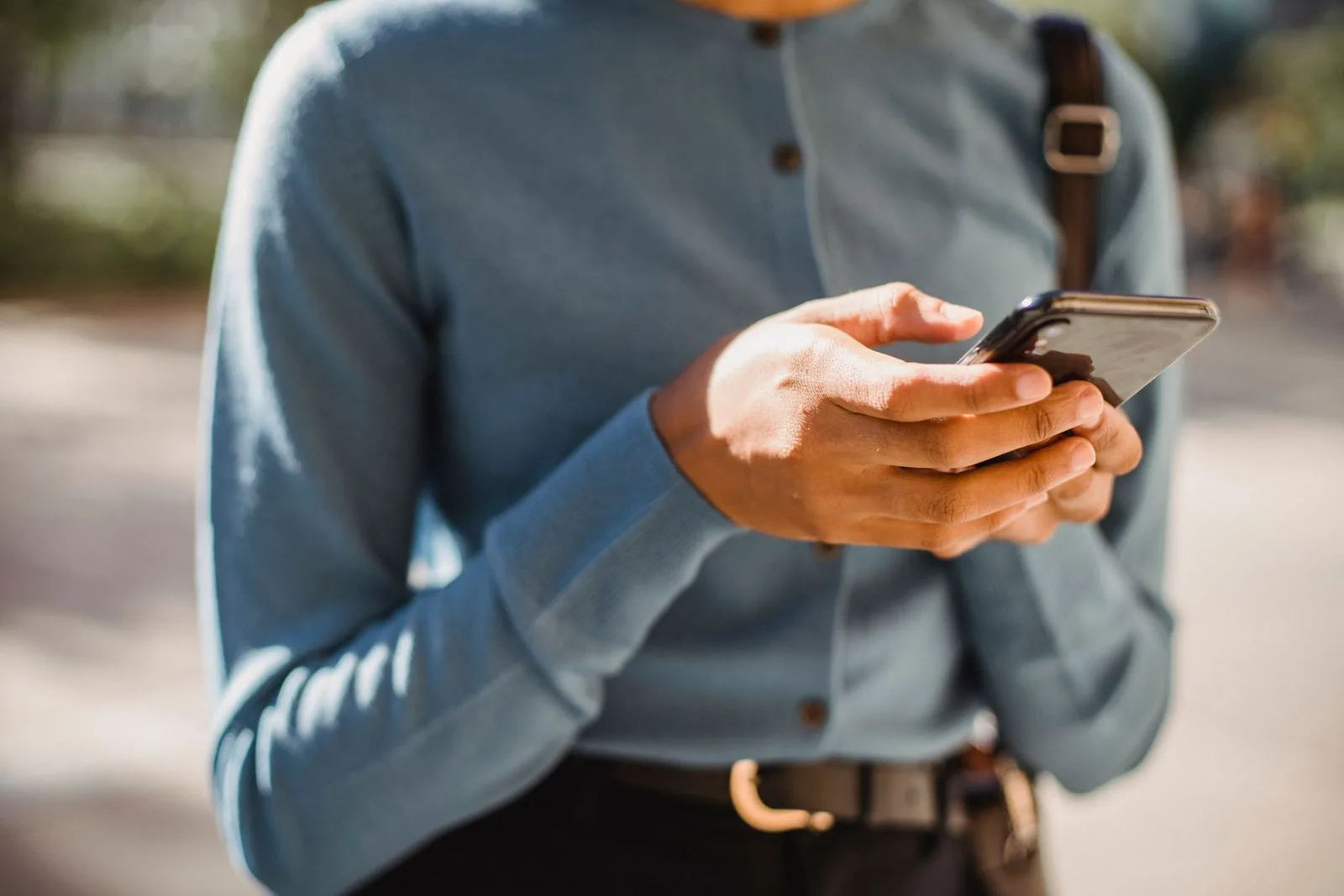 Dış mekânda akıllı telefon kullanan bir kişinin elleri.